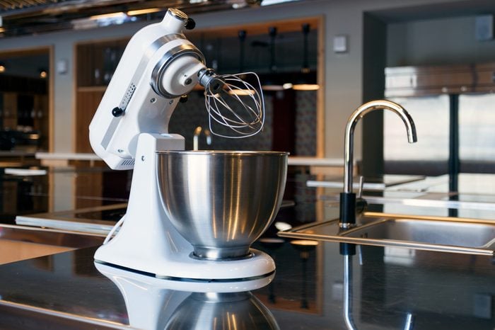 A beautiful white mixer with a metal cup stands in the modern kitchen