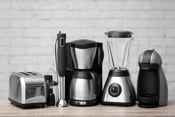 Kitchen appliances on table against brick wall background. Interior element