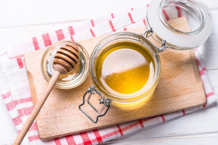 Honey in a jar with dipper on white