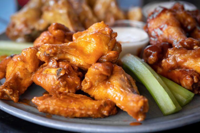 Close up on a platter of spicy buffalo chicken wings with space for text on the right