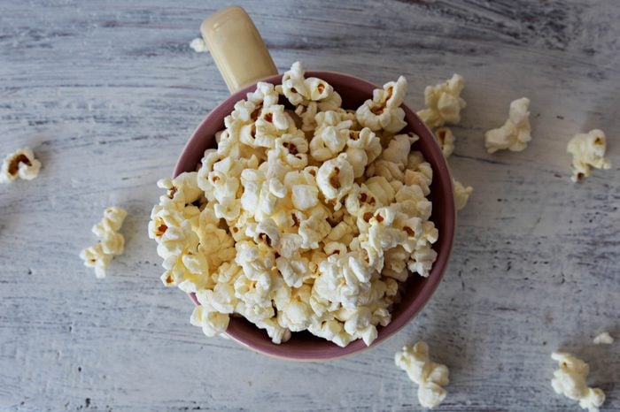 A bowl of delicious caramel popcorn on a white wooden background