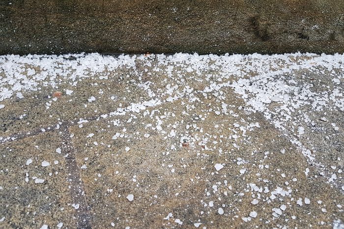 A lot of white salt is covered on the brown cement path to stop icy in the freezing night, feeling very cold. Concept salt, path and the safe in winter.