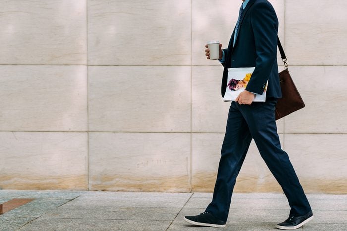 Cropped image of businessman with coffee and magazine going to work