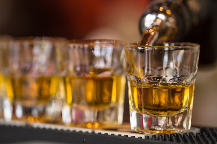 Barman makes whisky shot drinks in row. Alcoholic shots in nightclub