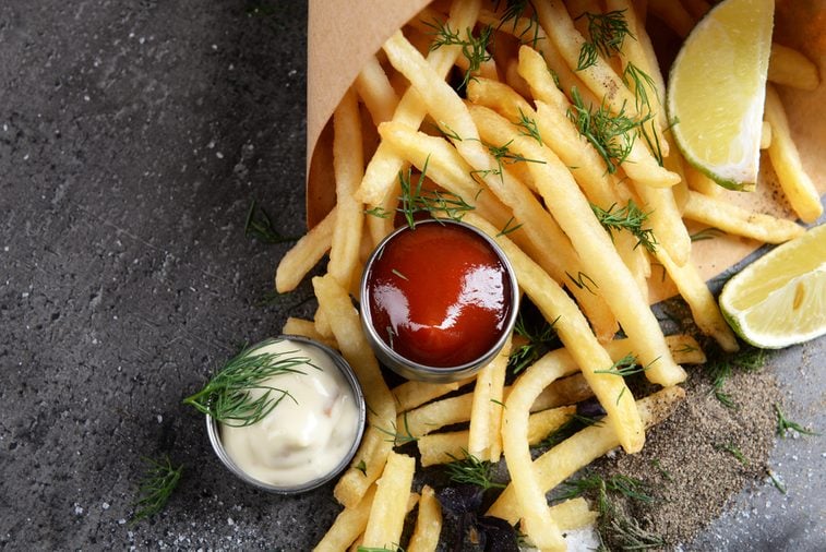 French fries in bag with sauce, lime and spice on table