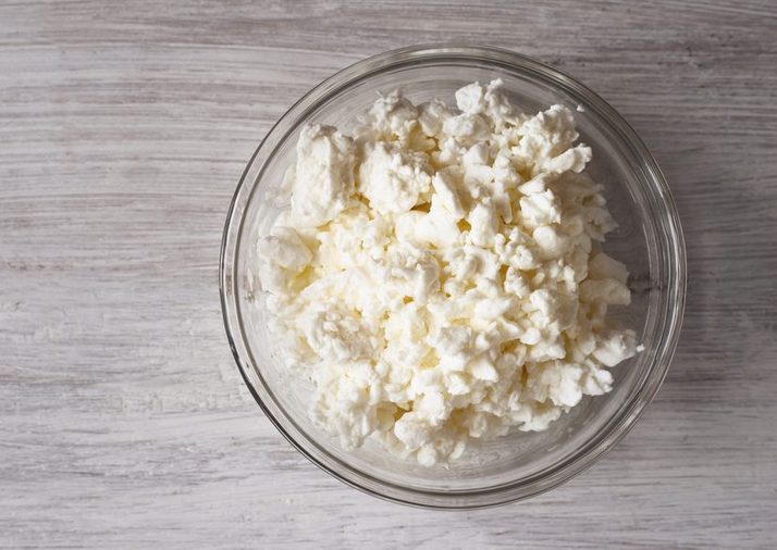 Cottage cheese in a glass bowl on a white wooden table