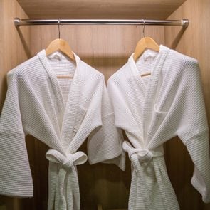two off white color bathrobes hanging in closet, room for copy space