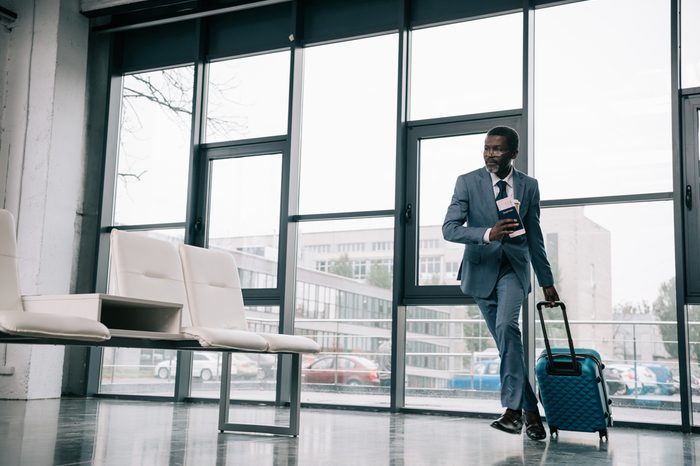 African american businessman hurrying up for flight at airport with wheeled bag