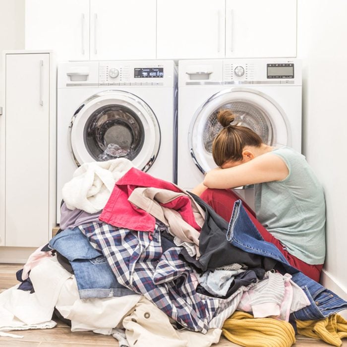 Sad woman sitting in laudry room with a pile of dirty clothes; Shutterstock ID 775801702; Job (TFH, TOH, RD, BNB, CWM, CM): Taste of Home