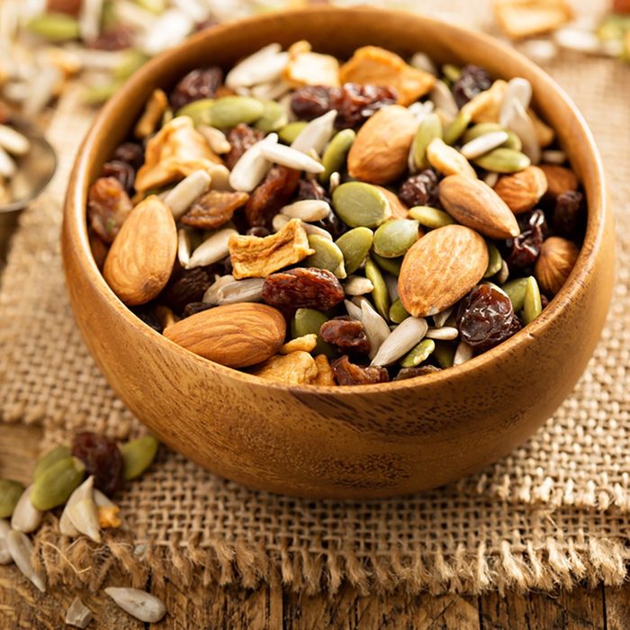 Dried fruit and nuts trail mix with almonds, raisins, seeds and apples in a wooden bowl