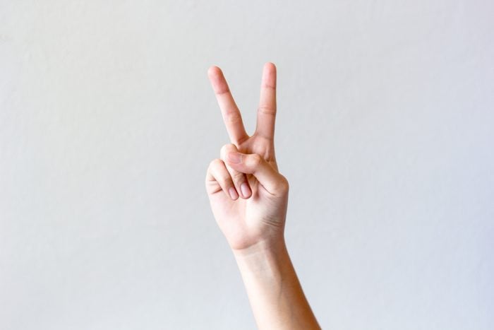 Woman hands isolated showing victory sign on grey background, gesture of victory.