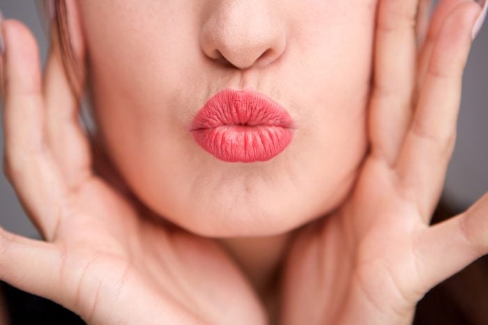 Close up portrait of young woman lips kissing