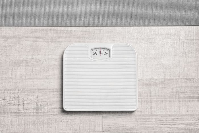 Bathroom scales and yoga mat on wooden background, top view. Weight loss concept