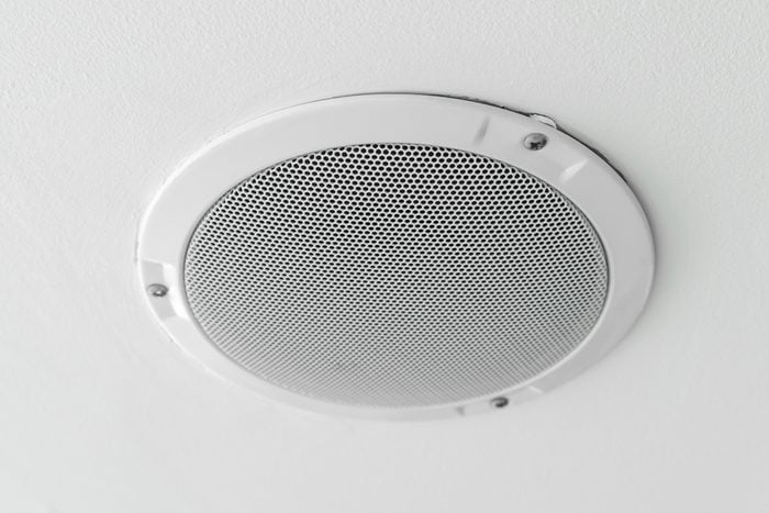 White round circle speaker and grille hanging on white ceiling