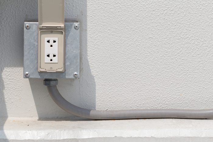 White Electrical Outlet or plug housing with waterproof cover at outdoor.