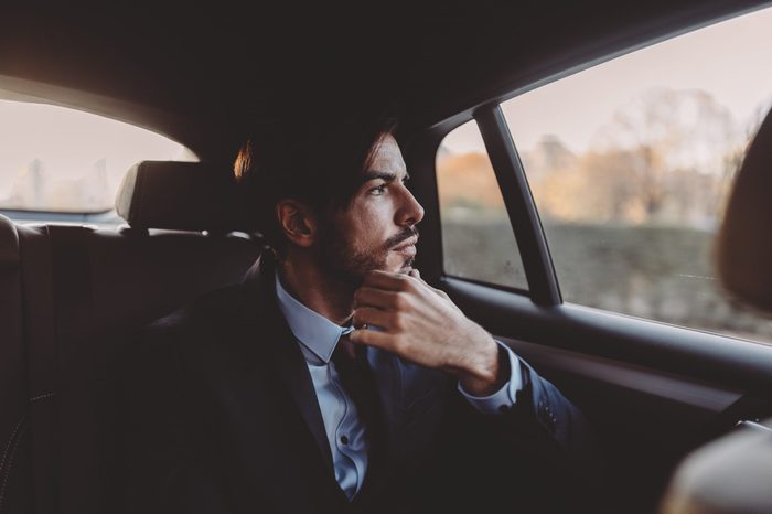 man looking pensively out the window of a taxi