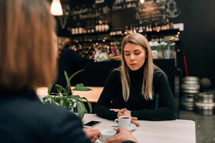 Two women in a cafe having a serious conversation over a cup of coffee