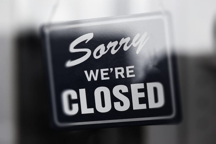 " Sorry we're closed " sign in monotone, with glass reflection. Shop glass door. Shallow depth of field.