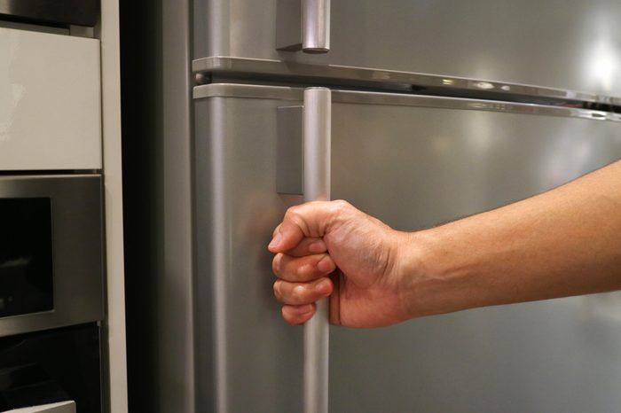 Abstract hand of a man is opening a refrigerator door