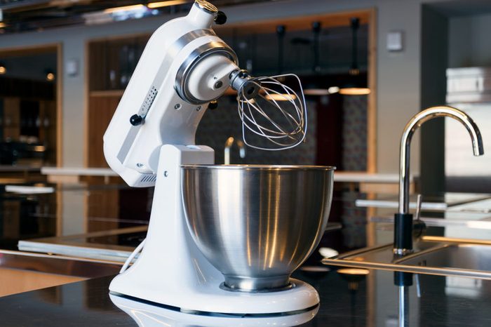 A beautiful white mixer with a metal cup stands in the modern kitchen
