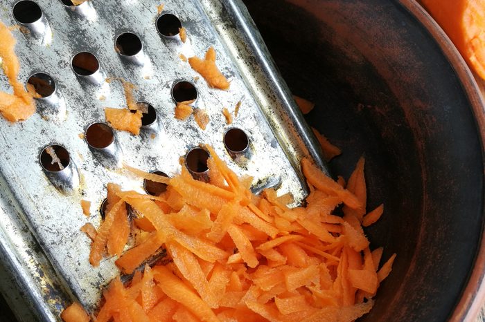 Carrots grated and old metal grater closeup