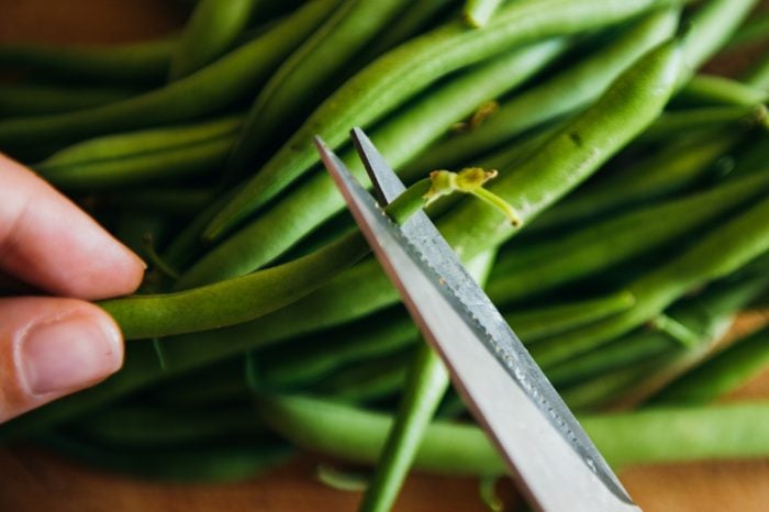 Green Beans on a grey concrete background wooden board cutting with scissors healthy food cooking
