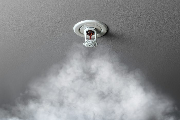 fire alarm sprinkler system in action with smoke