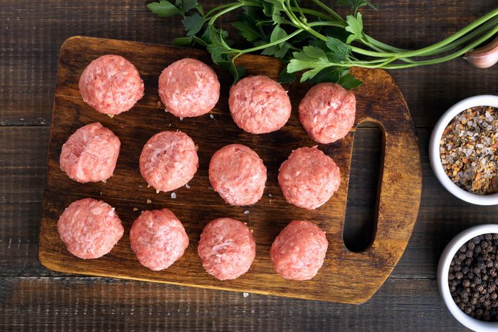 Raw meatballs on a cutting board, top view