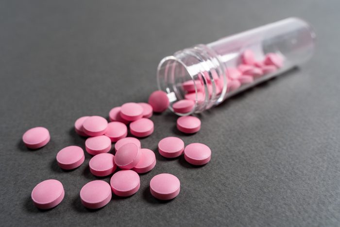 Pink medicine pills on a grey background.