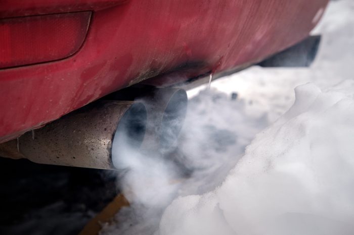 the exhaust gases of the car white thick smoke from the chimney in the winter against the white snow, pollution ecology