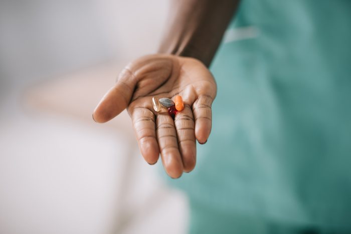 cropped view of african american woman holding pills in hand