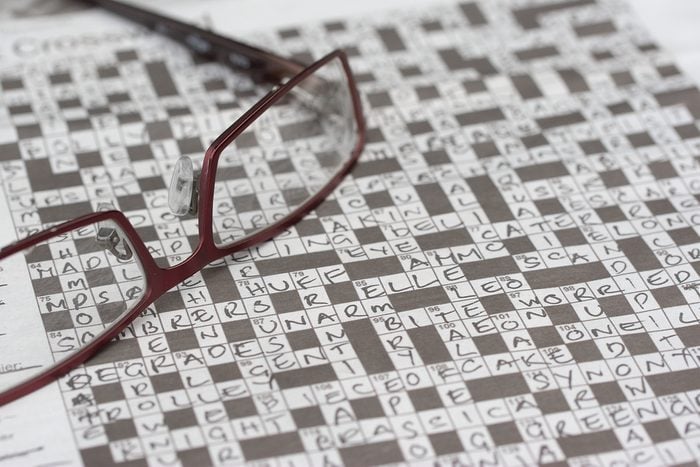 A completed crossword puzzle with a pair of reading glasses.