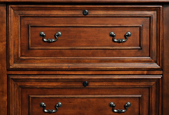 Beautifully crafted wood furniture. Detail of closed drawers with ornate pewter handles.