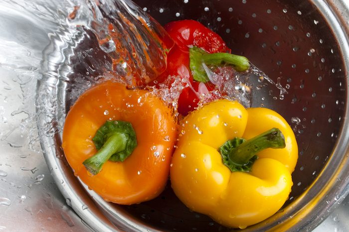 Yellow, red, and orange bell peppers washed in stainless steel metal colander
