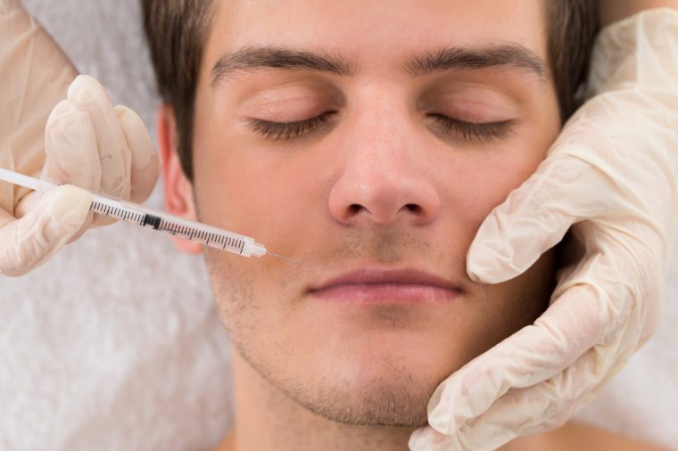 Close-up Of Doctor In Glove Giving Injection On Face Of Man In Clinic