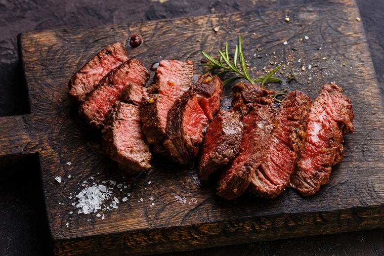 Sliced grilled steak roastbeef and rosemary on wooden cutting board background