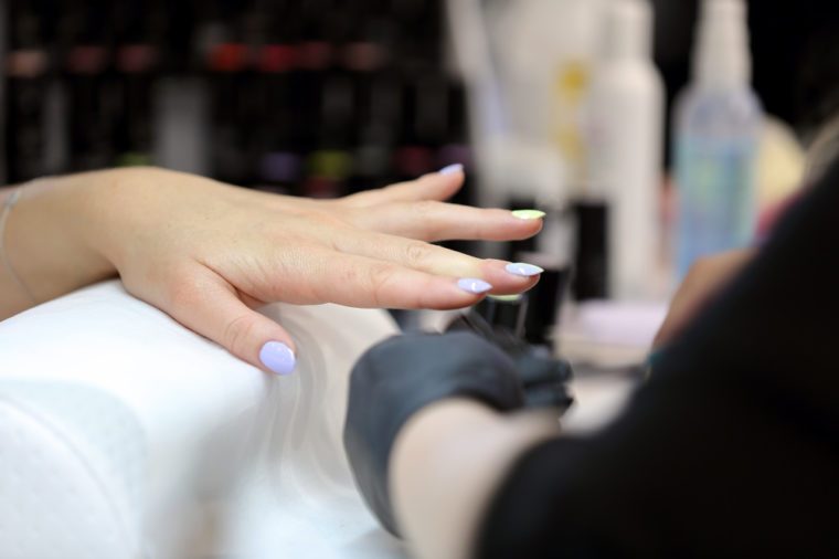 Manicurist master makes manicure on young woman hand