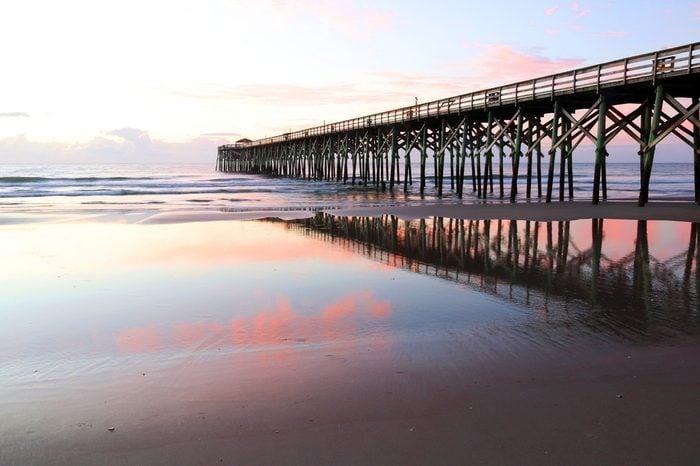 Early morning at deserted atlantic ocean beach. Marine landscape with wooden pier in South Carolina, Myrtle Beach area, USA.