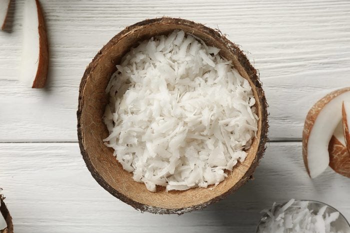 Grated coconut in shell on wooden background