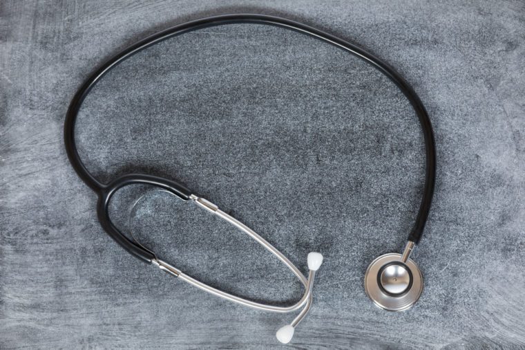 Healthcare, medical or cardiology concept with an overhead view of a coiled stethoscope on a textured grey background with central copy space