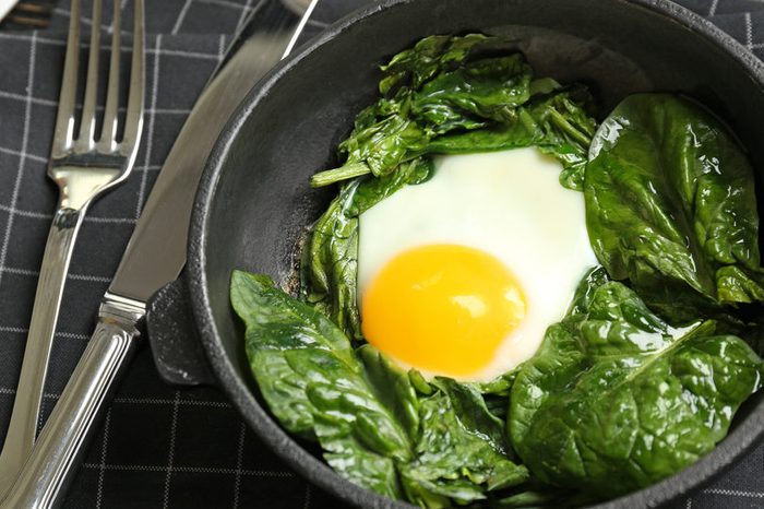 Delicious eggs Florentine in frying pan and napkin on wooden kitchen table