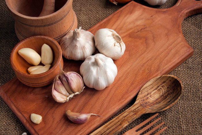 Garlic. sliced garlic, garlic clove, garlic bulb in wooden bowl place on chopping block on vintage wooden background. Place for text, copy space Concept of healthy food.