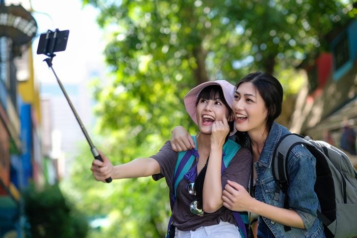 Close-up of excited cheerful smiling young beautiful girls in sunglasses taking selfie on summer city street. Urban life concept.Hipster girls wearing hat and sunglass enjoying selfie in colorful city
