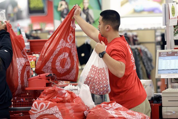 A Target employee hands bags to a customer at the register. 