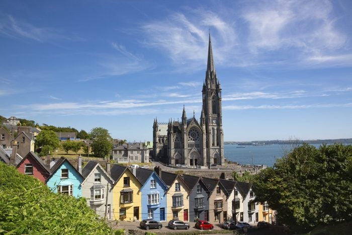 Ireland, County Cork, Cobh, Colorful Row Houses Standing Along Steep Street With Saint Colmans Cathedral In Background