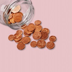 Jar of pennies spilling out on refective white