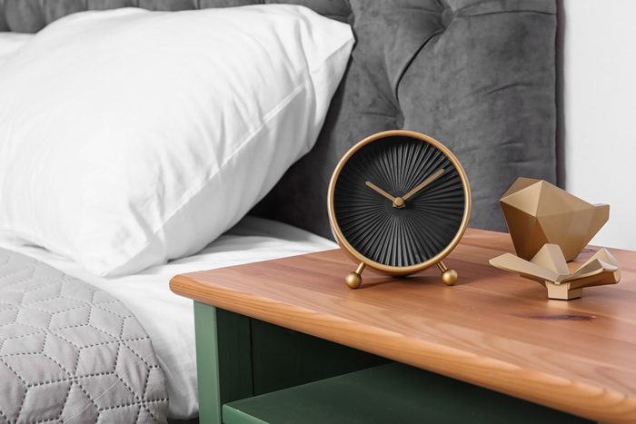 Stylish alarm clock and decor on nightstand in bedroom. Space for text