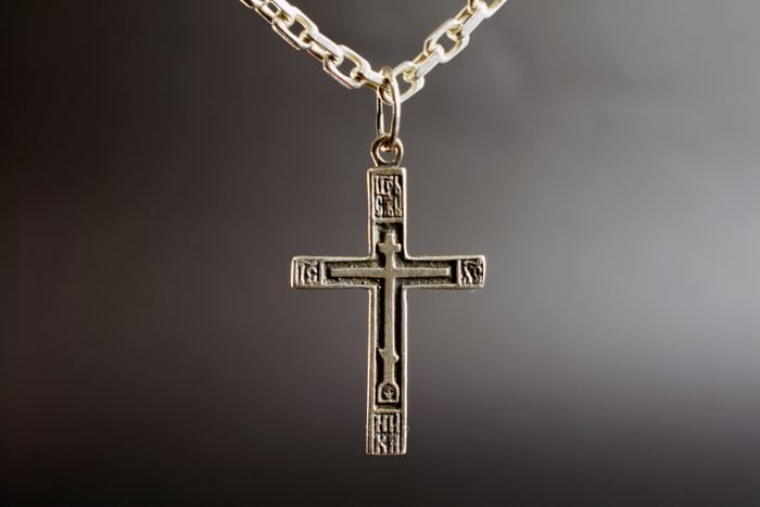christian cross on a silver chain, faith, spirituality and religion concept. selective focus, dark blurred background