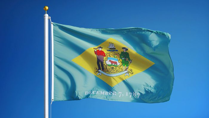 Açık mavi gökyüzüne karşı sallanan Delaware (ABD eyaleti) bayrağı, yakın plan, kırpma yolu maskesi alfa kanalı şeffaflığı ile izole edilmiş, film, haber, kompozisyon için mükemmel