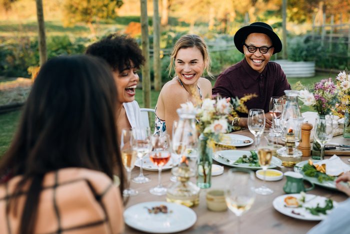 Group of friends enjoying outdoor party in home garden. Millennials  enjoying summer meal at restaurant.